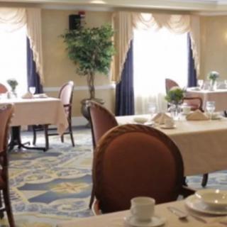 An elegant dining room with neatly arranged tables and chairs, adorned with decorative curtains and natural light filtering through the windows.