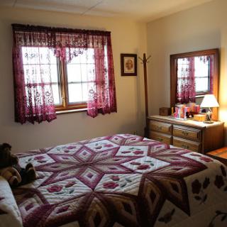 A cozy bedroom featuring a beautifully patterned quilt and warm lighting.