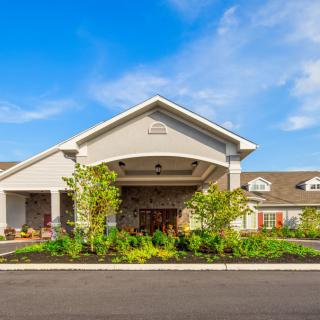 A modern building entrance with well-maintained landscaping under a clear blue sky.