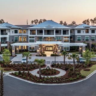 A luxurious residential building with beautiful landscaping and a grand entrance viewed during sunset.