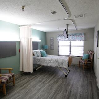 A serene hospital room designed for patient comfort, featuring a bed, seating area, and natural light from the window.