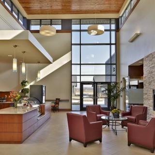 A modern lobby interior with comfortable seating and a reception desk, illuminated by natural light through large windows.