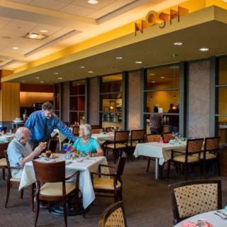 A cozy restaurant interior with people dining and a waiter serving at the tables.