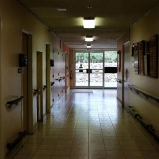 A view down a hospital corridor with doors leading to various rooms.
