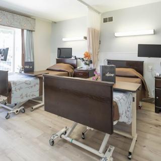 A bright and clean hospital room with two patient beds, equipped with medical furniture and amenities.