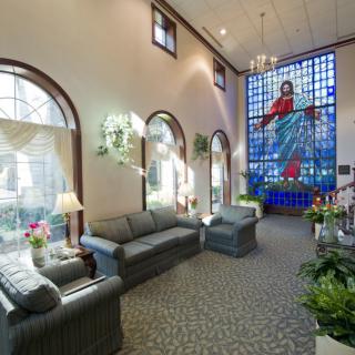 A cozy lobby area featuring comfortable sofas, large arched windows, and a vibrant stained glass artwork.