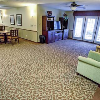 A spacious living room with carpet flooring, a dining area, and various pieces of furniture.