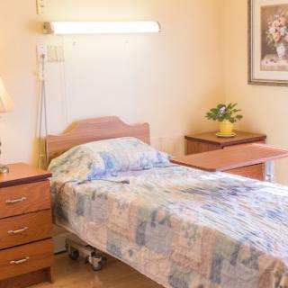 A cozy hospital room featuring a single bed, bedside table, and decorative elements.