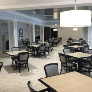 An empty cafeteria with neatly arranged tables and chairs.