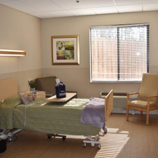 A clean and well-organized hospital room with a patient bed, chair, and window.