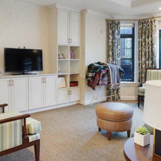 A cozy living room with a television, bookshelf, and comfortable seating.