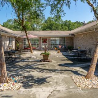 A tranquil courtyard with outdoor seating, surrounded by trees and a residential building.