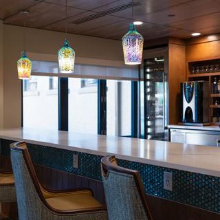 A modern bar area with colorful pendant lights and comfortable seating.