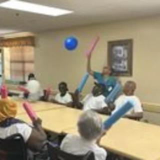 A group of seniors participating in an indoor activity with balloons.