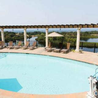 A scenic outdoor pool area with lounge chairs and a pavilion overlooking a natural landscape.