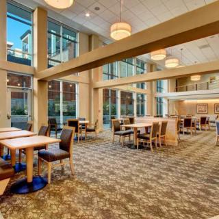A modern dining area with large windows and comfortable seating.