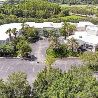 Aerial view of a building surrounded by trees and a parking lot.