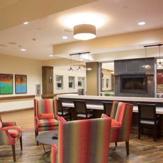 A modern lobby area featuring colorful chairs and a central fireplace.