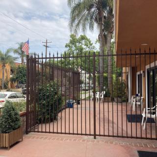 A gated patio area with chairs and plants, bordered by a metal fence and palm trees.