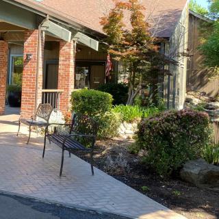 A charming patio with chairs beside a brick building surrounded by lush greenery.
