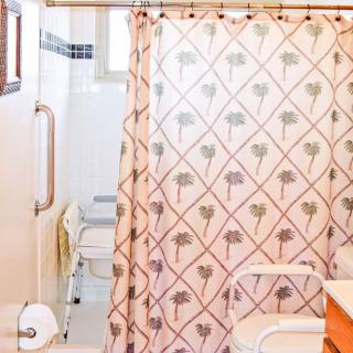 A bathroom with a patterned shower curtain and accessible features.