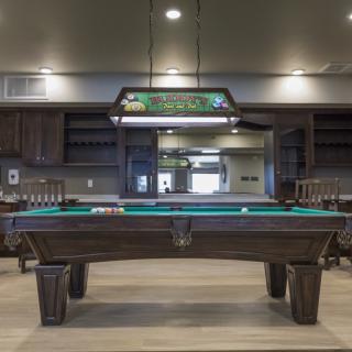 A stylish game room featuring a billiard table with a hanging light fixture above.