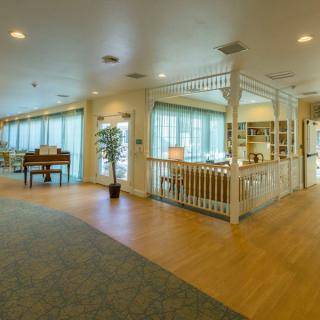 A spacious and bright living area featuring a piano, bookshelves, and comfortable seating.