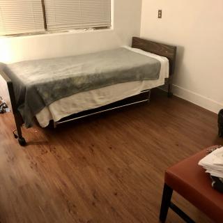 A simple and minimalist bedroom with a single bed and wooden flooring.
