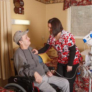 A caregiver attending to an elderly patient in a comfortable healthcare setting.