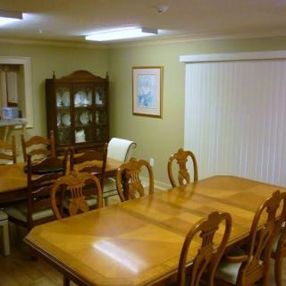 A dining room with wooden tables, chairs, and a cabinet.