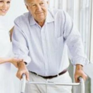 An elderly man using a walker with the assistance of a caregiver.
