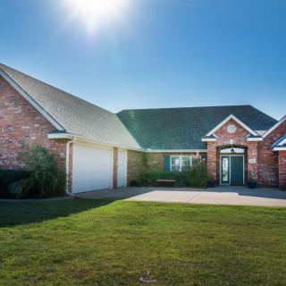A sunny day view of a residential brick house with a driveway and a two-car garage.