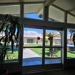 A bright interior view showcasing large windows with a glimpse of the outdoor landscape, adorned with plants.