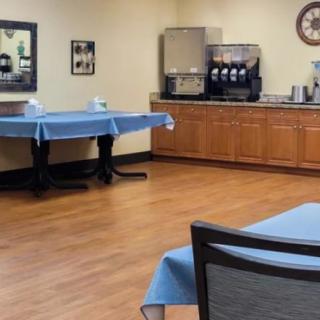 A quiet dining area with tables covered in blue tablecloths and a coffee machine in the corner.