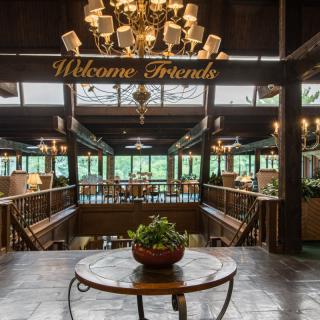 A warmly decorated lobby with a chandelier and a 'Welcome Friends' sign.