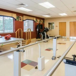 A well-equipped rehabilitation room with exercise equipment and walking bars.