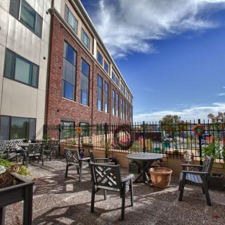 An outdoor patio area with seating and tables next to a building under a clear blue sky.