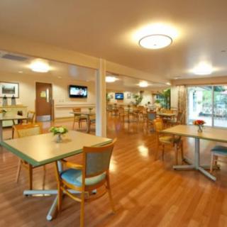 A spacious dining area with wooden floors, tables, and chairs.