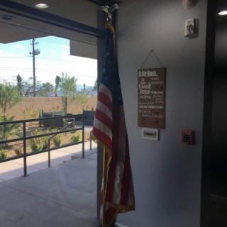 An American flag placed inside a building near the entrance, accompanied by a sign on the wall.