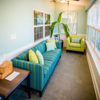 A bright and airy living room with a striped sofa and armchair, featuring natural light and green accents.