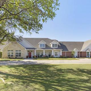 A large suburban house with a well-kept lawn and clear blue sky.