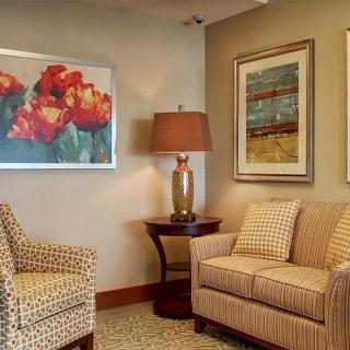 A cozy living room corner with patterned sofas, a table lamp, and two pieces of artwork on the wall.
