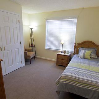 A cozy bedroom with a single bed, lamp, and closet.