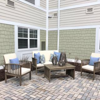 A cozy outdoor patio seating area with cushioned chairs and a coffee table on brick flooring.