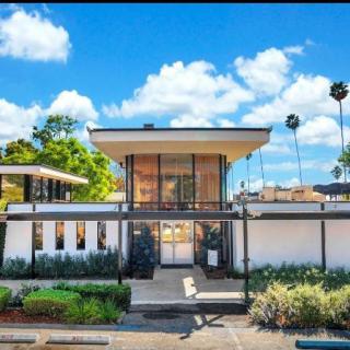 A modern mid-century style house with a landscaped yard under a bright blue sky.