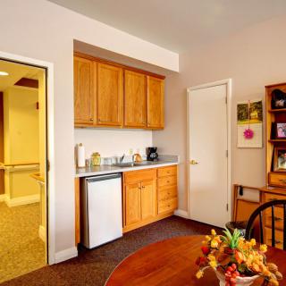 A cozy kitchenette area in an apartment with wooden cabinets and a small fridge.