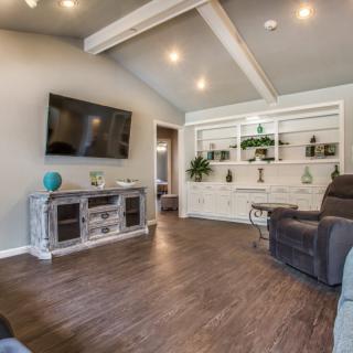 Modern living room with hardwood flooring and a large television.