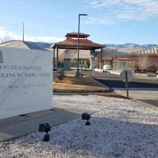 An exterior view of a facility featuring a prominent sign, with mountains in the background.