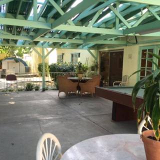 A sunny backyard patio with a pergola, outdoor furniture, and potted plants.