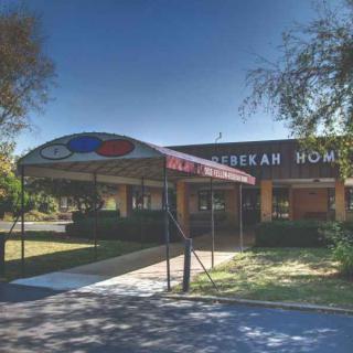 A funeral home with an awning at the entrance, surrounded by trees on a sunny day.